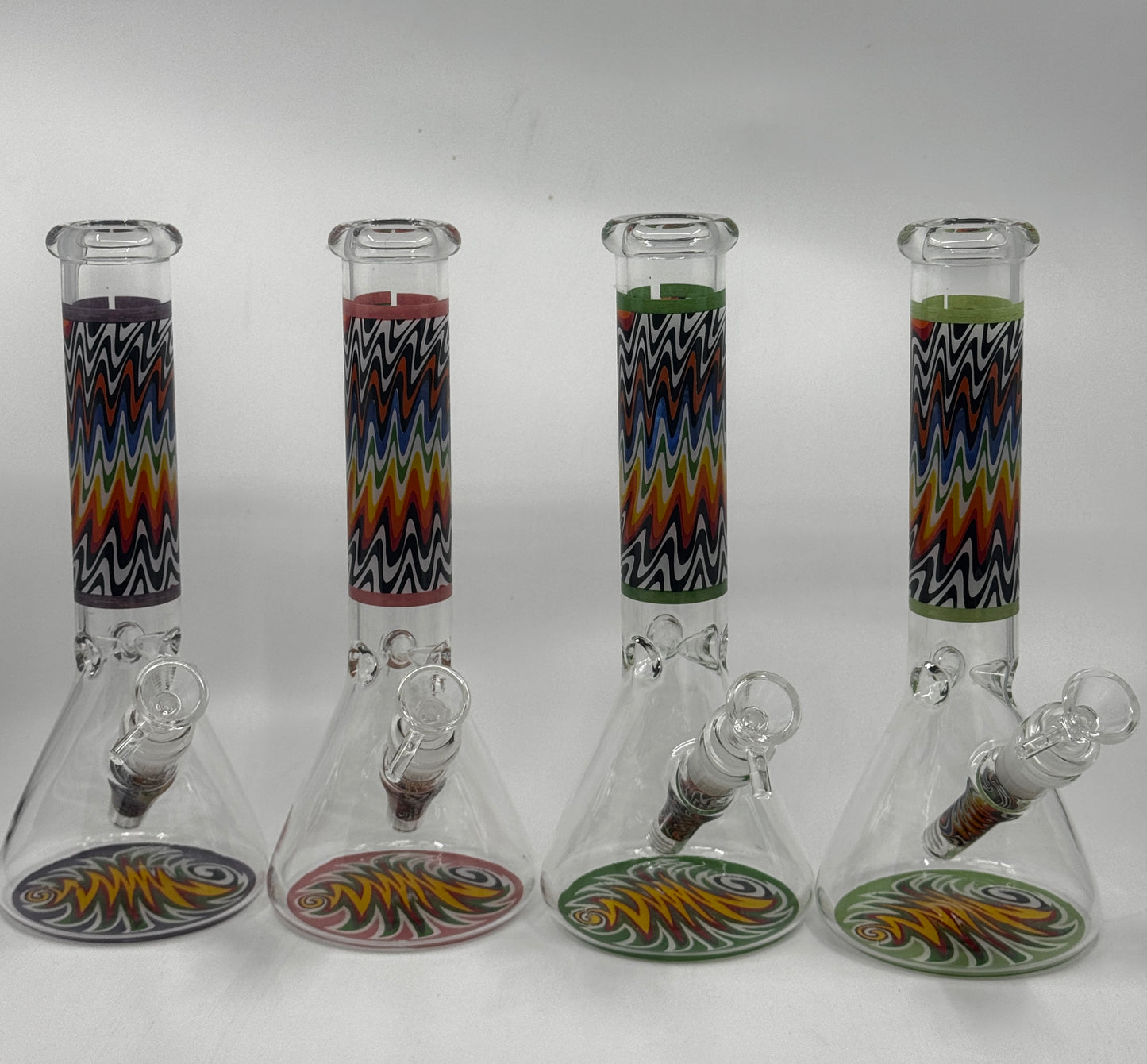 Four glass beakers with colorful zigzag patterns on a white background