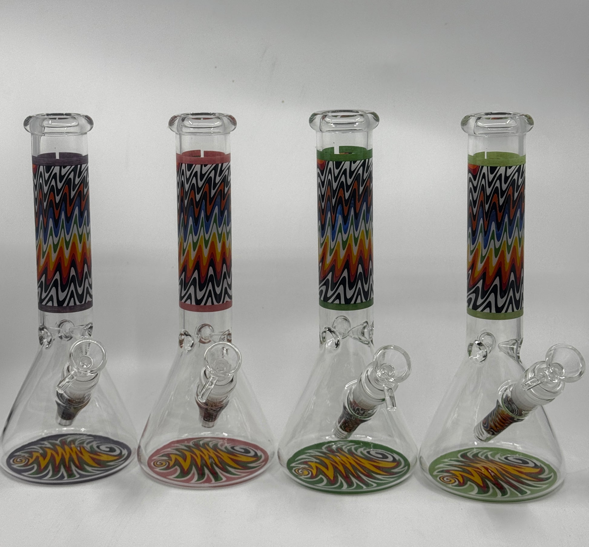 Four glass beakers with colorful zigzag patterns on a white background