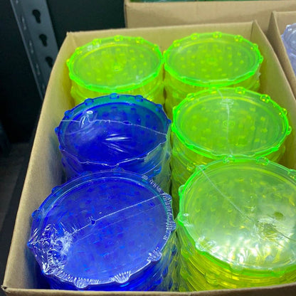 Colorful herb grinders in blue and yellow stacked in a box for those looking to buy herb grinder online USA
